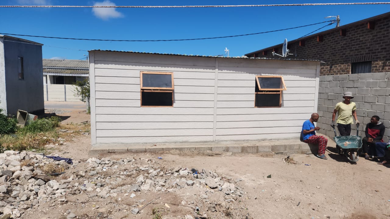 A white Nutec structure with wooden windows installed on a concrete base
